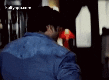 a man in a blue shirt is standing in front of a red light in a dark room .