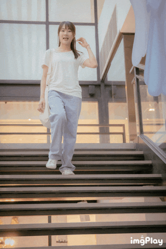 a woman walking down a set of stairs with imgplay written on the bottom right