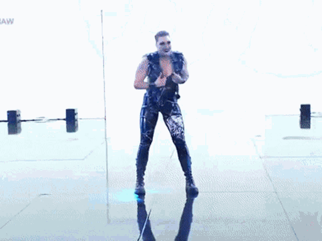 a man in a black outfit is dancing on a stage with the word raw on the bottom