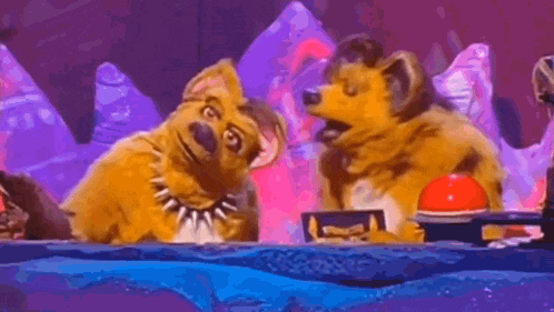 two cartoon dogs are sitting next to each other on a stage in front of a purple background .
