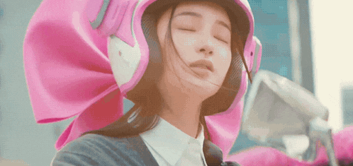 a woman wearing a pink helmet with her eyes closed .