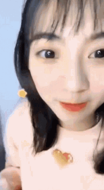 a close up of a woman 's face with a heart shaped necklace on her neck