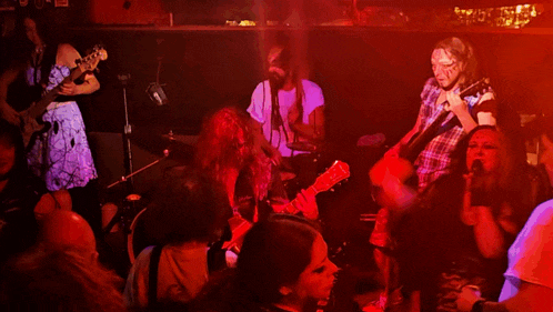 a man in a plaid shirt is playing a guitar in front of a crowd