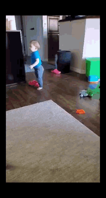 a little boy is standing on a wooden floor