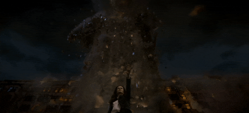 a woman is standing in front of a large object that is flying through the air