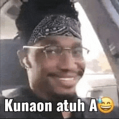 a man wearing glasses and a headband is smiling in a car .