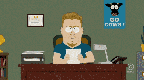 a man sitting at a desk with a sign that says go cows on it