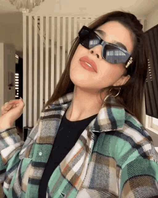 a woman wearing sunglasses and a plaid shirt is taking a picture