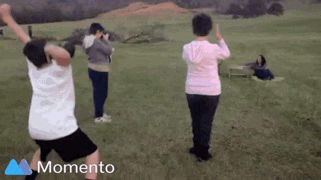 a group of people dancing in a field with the word momento on the bottom left