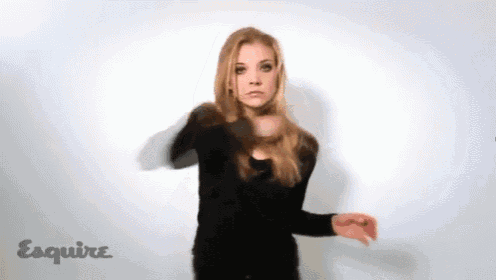a woman in a black shirt is dancing in front of a white wall with esquire written on it