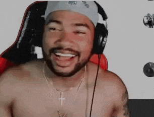 a shirtless man wearing headphones and a cross necklace is sitting in a chair .