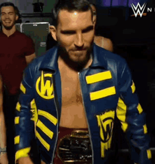 a wrestler is wearing a blue and yellow jacket with the letter w on it .