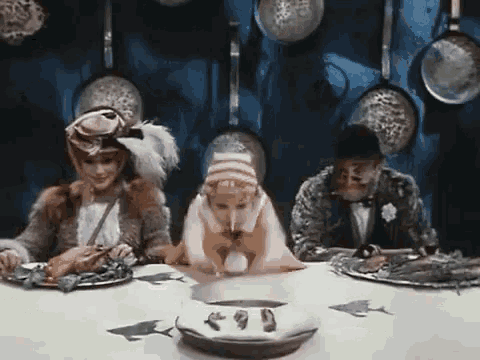 a group of people sitting at a table with plates of food .