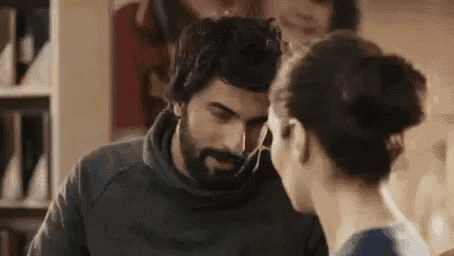 a man with a beard is kissing a woman on the forehead in a room .