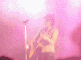 a man is playing a guitar in front of a microphone on a stage .