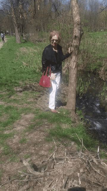 a woman kneeling next to a tree with a dog on the ground