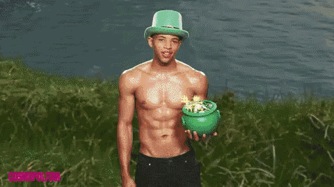 a shirtless man in a green hat is holding a pot of gold and a rainbow is coming out of it