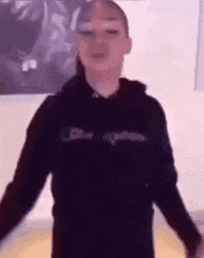 a person wearing a black hoodie is standing with their arms outstretched .