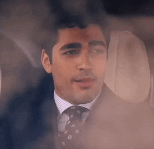 a man in a suit and tie is looking out the window of an airplane