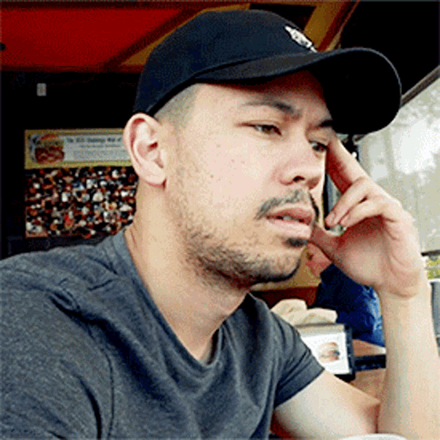 a man wearing a black hat and a grey shirt looks to his left