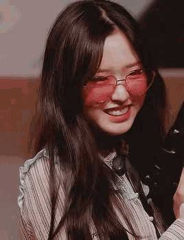 a close up of a girl wearing pink sunglasses and smiling .