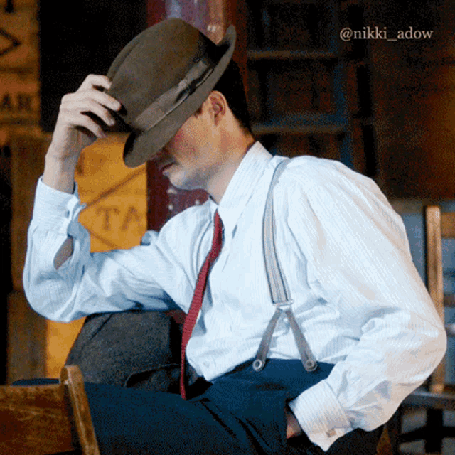 a man wearing suspenders and a hat with the name nikki adow on the bottom