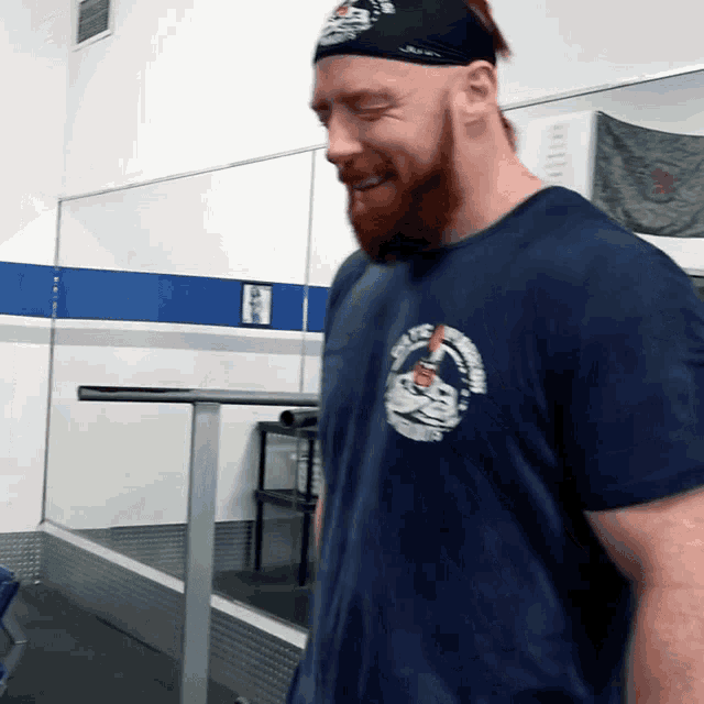 a man with a beard wearing a headband and a blue shirt that says ' united states marines ' on it