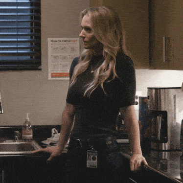 a woman in a kitchen stands in front of a sign that says how to hand out