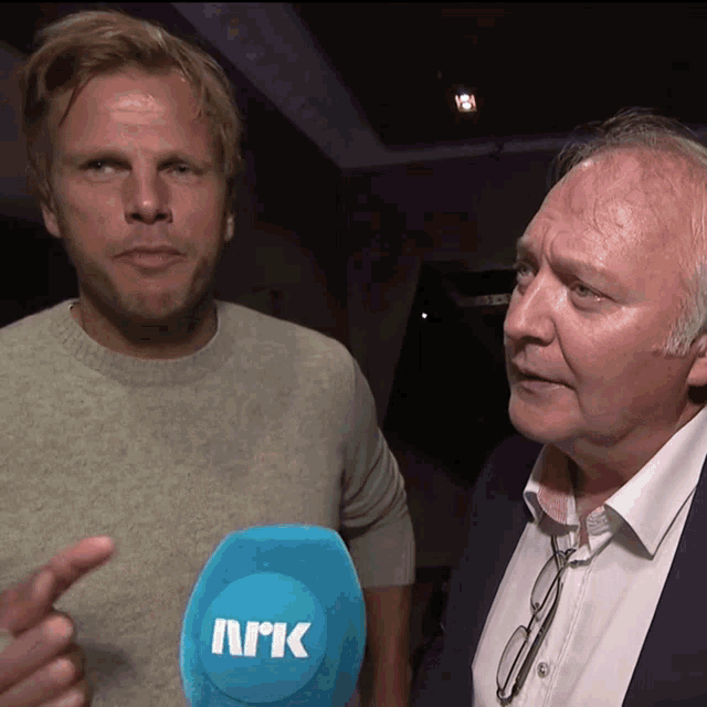 two men standing next to each other with a blue microphone that says ark