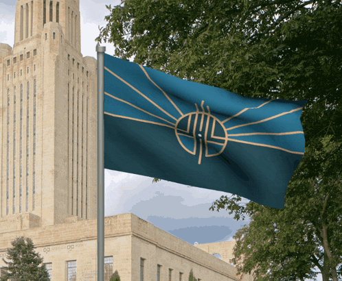 a blue and gold flag is flying in front of a tall building