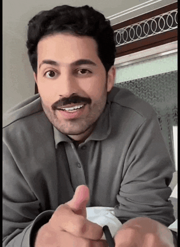 a man with a beard and mustache is smiling and giving a thumbs up