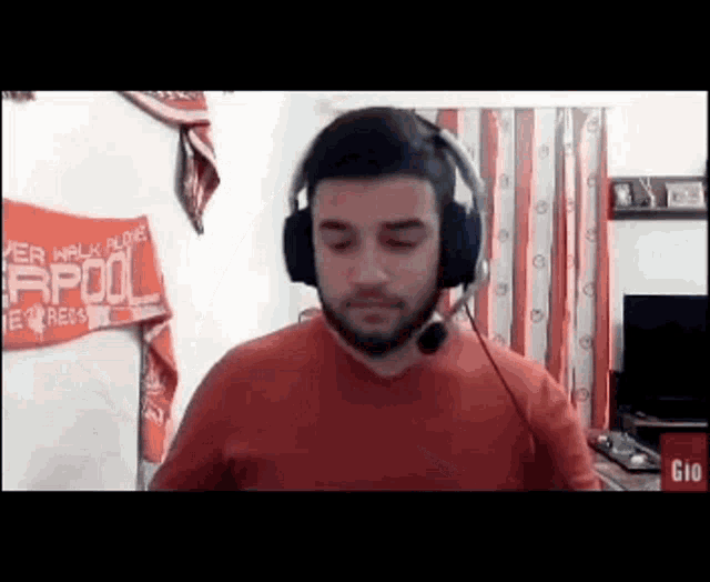 a man wearing headphones and a microphone is standing in front of a sign that says liverpool .