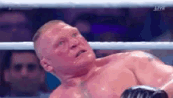 brock lesnar is laying on the ground in a boxing ring during a match .