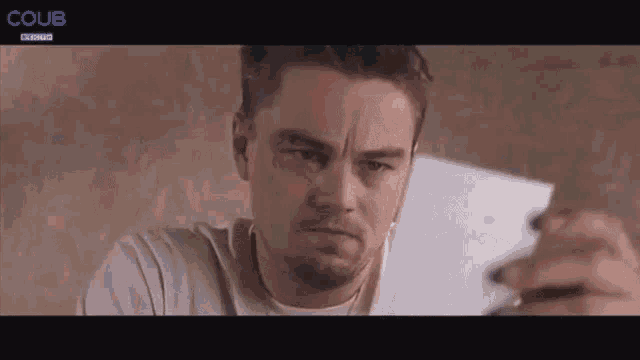 a man is holding a piece of paper in his hand and making a face .