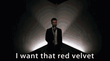 a man in a suit is singing into a microphone while standing in a dark room .
