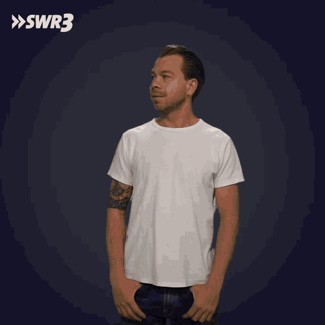 a man in a white shirt stands with his hands in his pockets in front of a blue background with the letters swr3