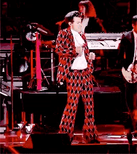 a man in a plaid suit is dancing on a stage