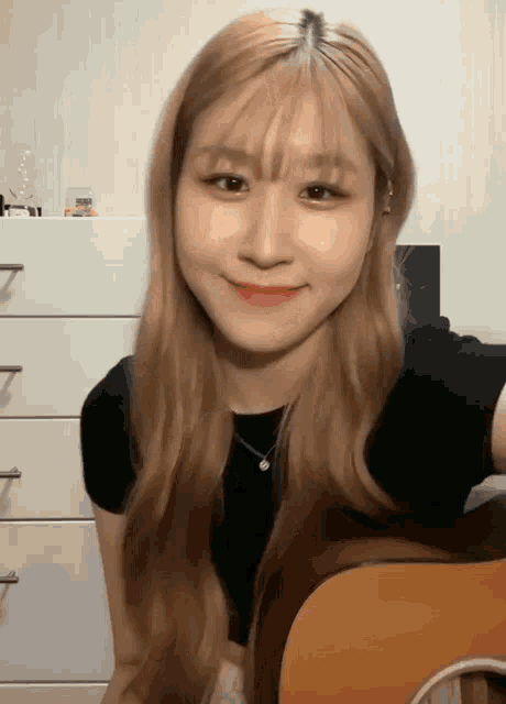 a woman with long blonde hair is holding a guitar and smiling
