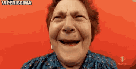 an elderly woman is making a funny face in front of a red background with the words viperissima written on it .