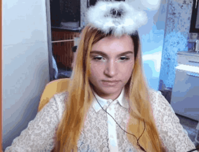 a woman with long blonde hair is wearing a white angel 's halo on her head .