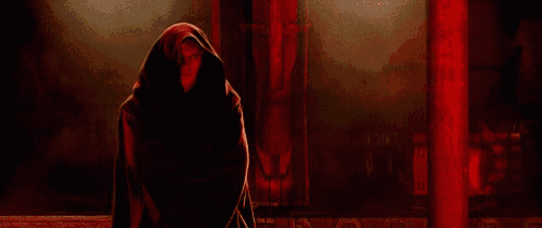 a man in a black robe is standing in a dark room .