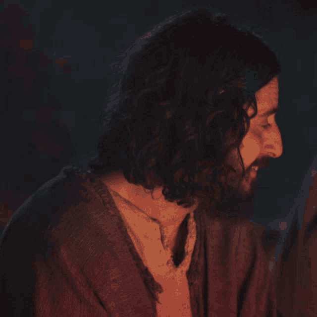 a man with long hair and a beard looks down at something
