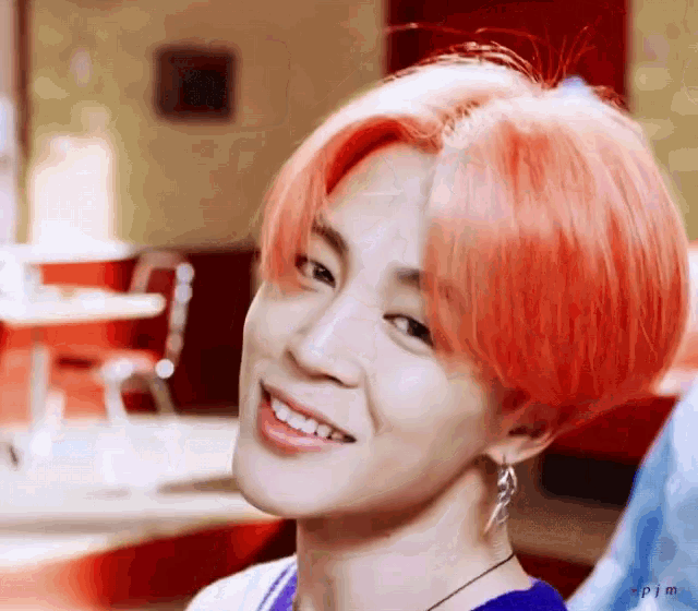 a young man with bright red hair is smiling in a restaurant .