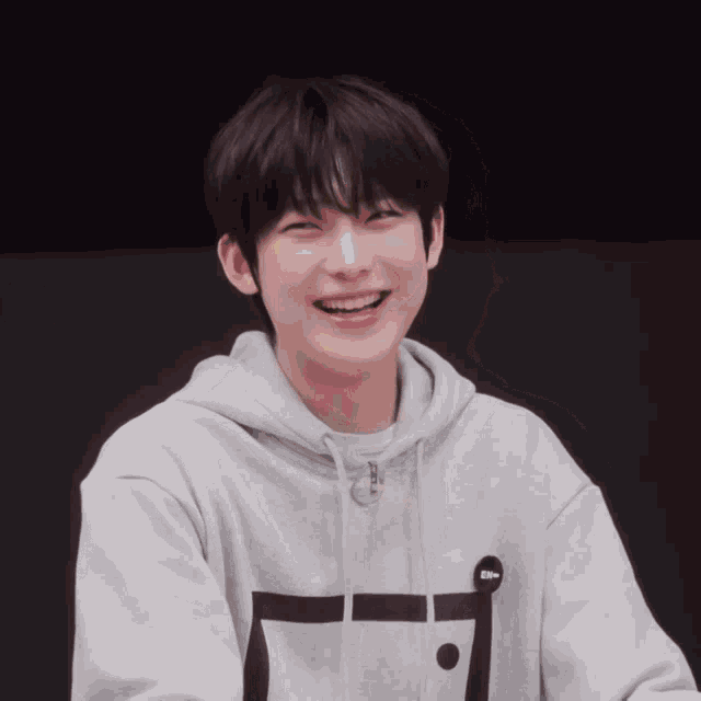 a young boy wearing a grey hoodie with the letter e on the front