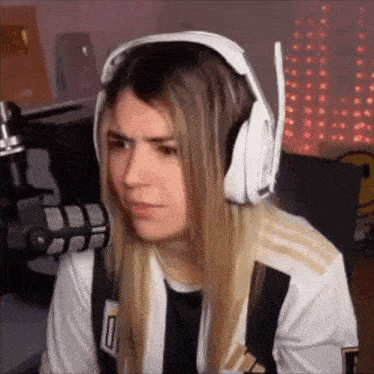 a woman wearing headphones and a black and white shirt is making a funny face .