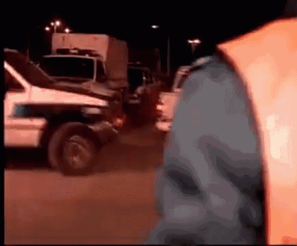 a person wearing an orange vest is standing in front of a police car