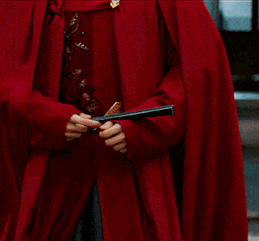 a man wearing a red cape holds a book