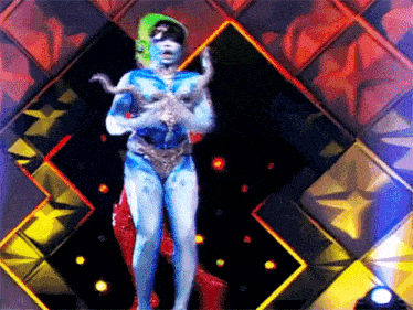 a woman in a blue body painted costume holding a snake