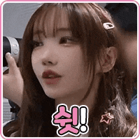 a girl is holding a camera in her hand and looking at the camera .