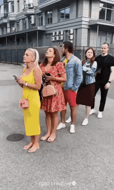 a group of people standing in a line with xpto creative written in the corner